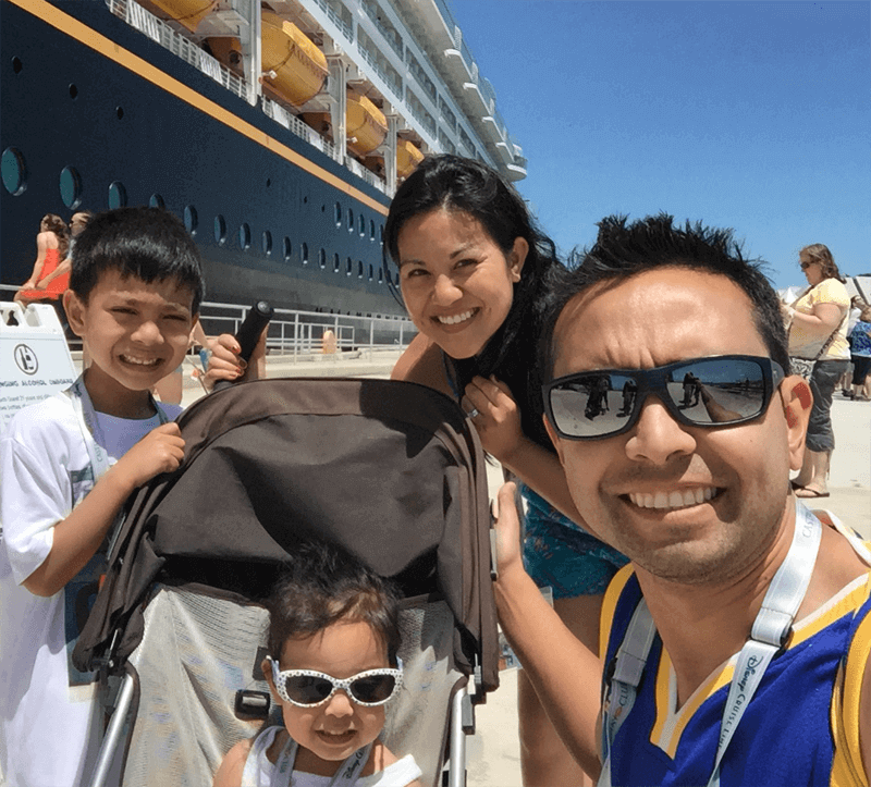 Photo of Pat, his wife April, young son Keoni, and toddler daughter Kai in a stroller, in front of a cruise ship