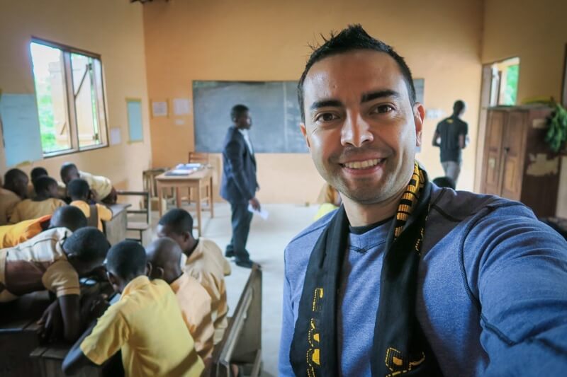 Pat in a Pencils of Promise Classroom in Ghana. Groups of students are working together at tables.