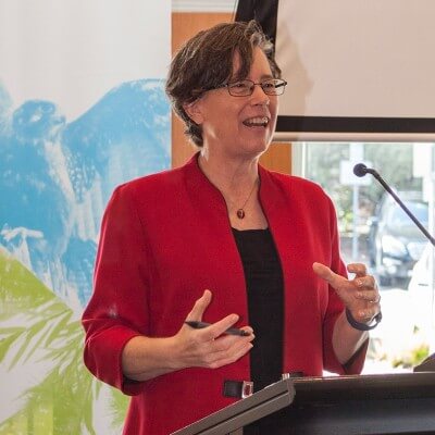 Image of Trudy standing at a lectern, speaking 