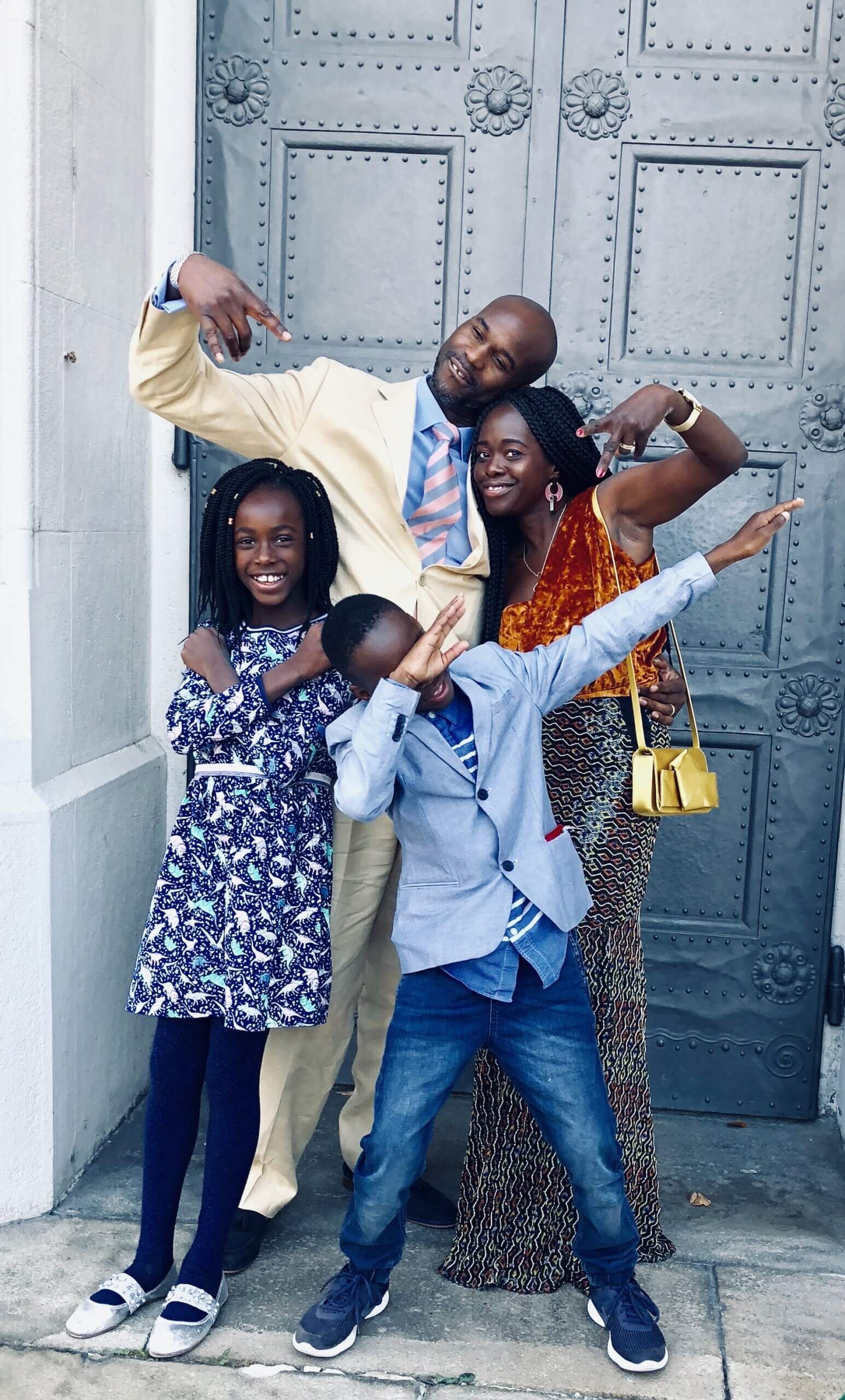 Picture of Kolarele in front of a big iron door, with wife, and two middle school aged kids (girl and boy)