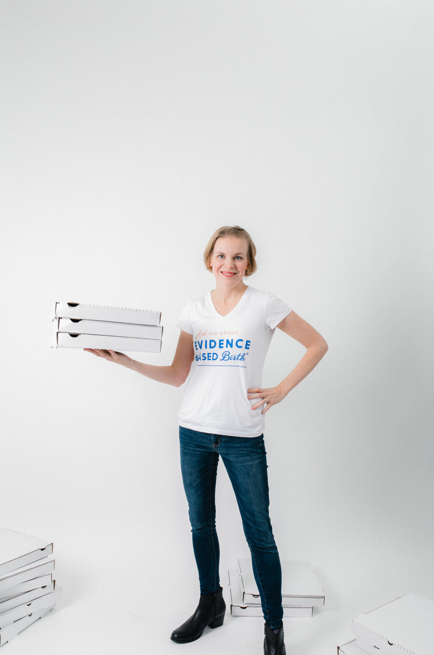 Rebecca Dekker standing while holding three pizza boxes