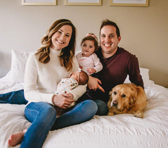 Photo of Josh posing with wife, toddler daughter, infant, and golden retriever