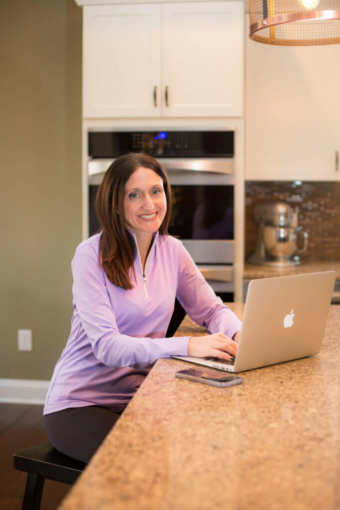 Rose Griffin sitting at her computer on a kitchen counter