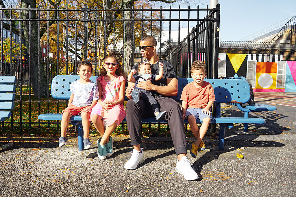 Terry Rice sitting on a park bench with his four cute kids