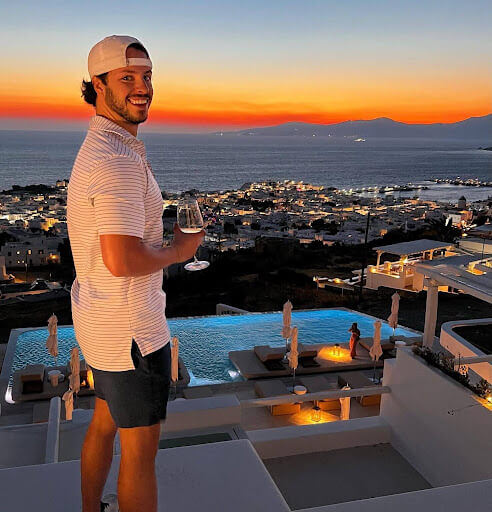 Brian Luebben smiles with a glass of wine while enjoying a sunset — one of the perks of full-time travel