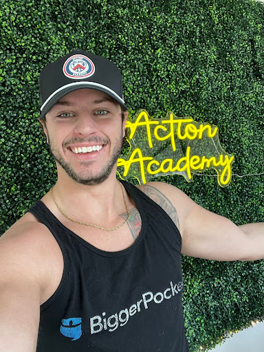 Brian Luebben, who successfully quit his job to travel full-time, smiles with an Action Academy logo