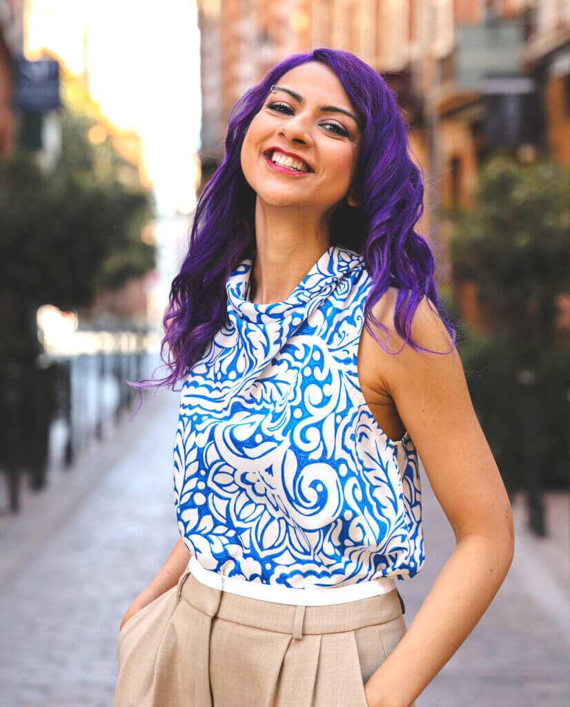 Nausheen I. Chen poses in the street while wearing a patterned shirt.